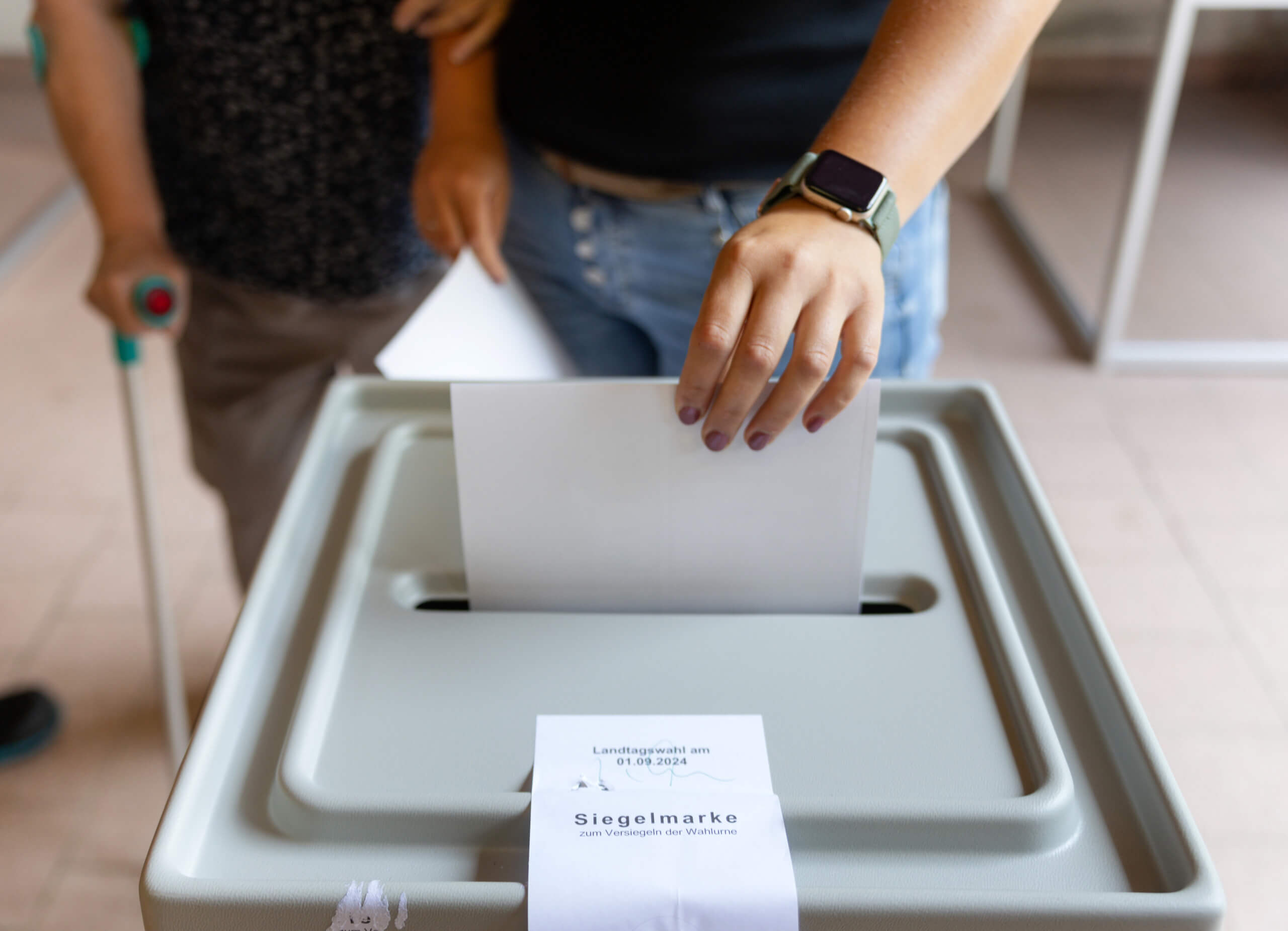 Eine Frau wirft einen Wahlschein in eine Urne