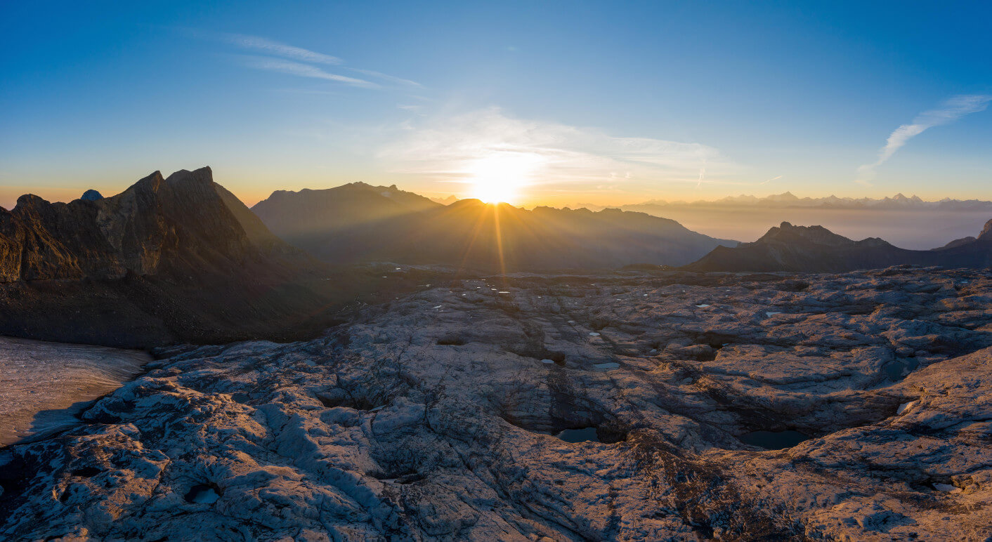 Luftaufnahme über dem Gletscher-Vorfeld des Zanfleuron-Gletscher mit aufgehender Sonne, Kanton Wallis, Schweiz, Europa