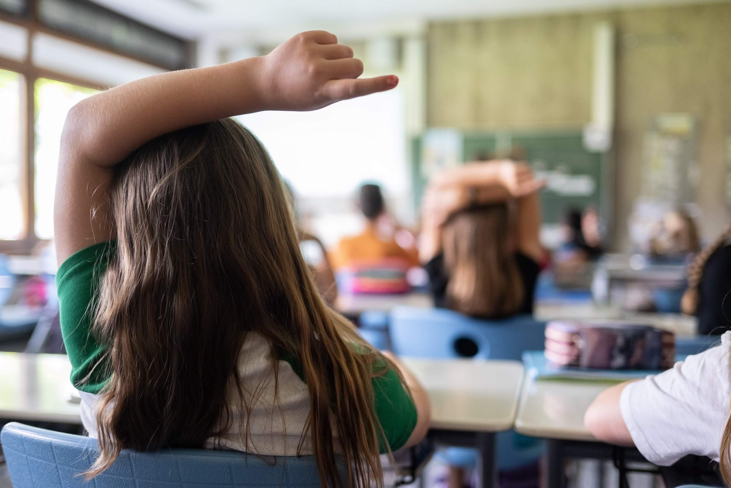 Kinder sitzen im Klassenraum, ein Kind meldet sich. Eine Million Schülerinnen und Schüler sollen durch das Förderprogramm bis 2034 besser schreiben, lesen und rechnen können.