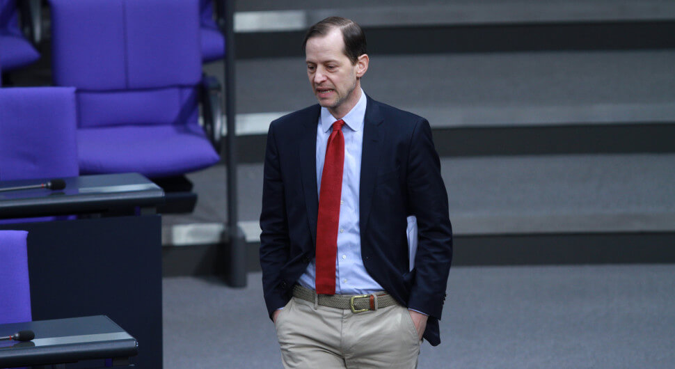 Der AfD-Abgeordnete Roger Beckamp steht mit gesenktem Kopf und im Anzug im Bundestag. Foto: picture alliance