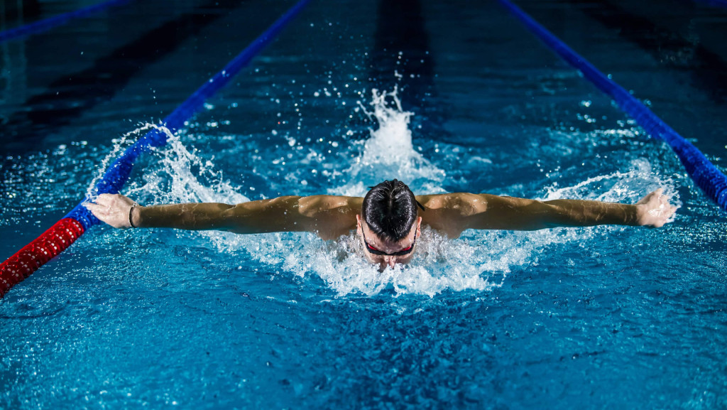 Ein Mann schwimmt in einem Hallenbad Bahnen