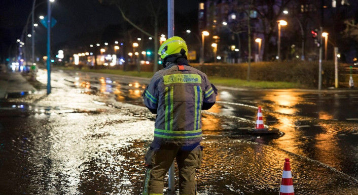 Feuerwehrmann steht auf einer überschwemmten Straße im Wedding in Berlin in der Silvesternacht