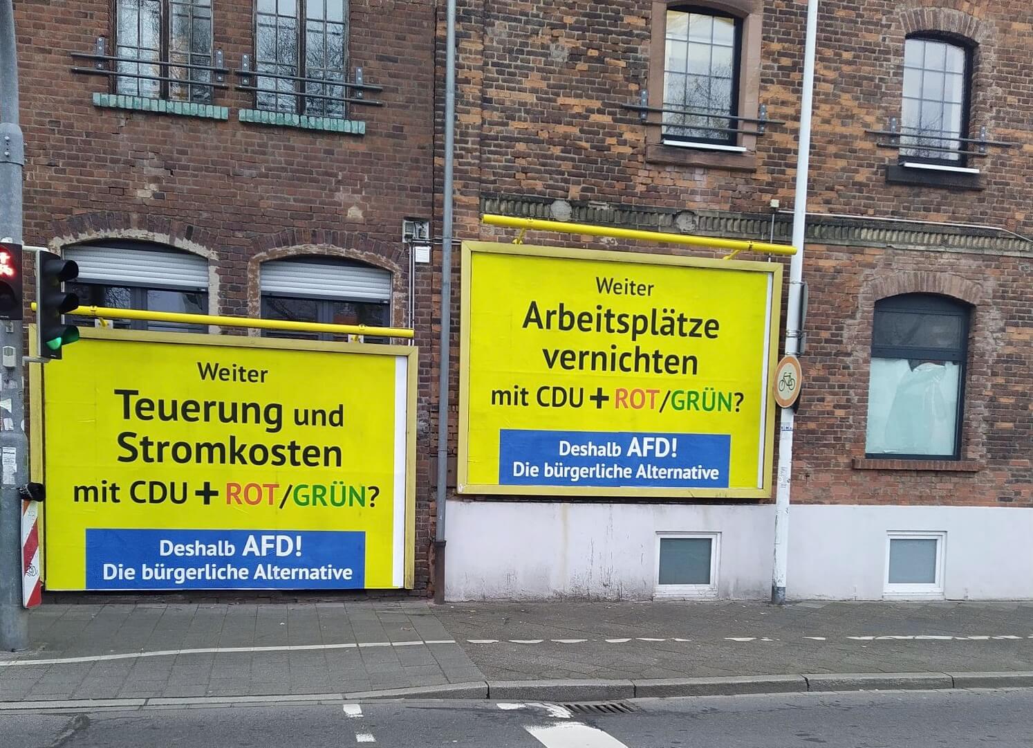 Gelber Hintergrund, alarmierender Text: An einer Straßenkreuzung in Darmstadt hängen seit dieser Woche zwei AfD-Unterstützerplakate, bundesweit sollen es Tausende sein. Auf dem Foto zu sehen ist u.a. der Slogan „Weiter Arbeitsplätze vernichten mit CDU, SPD, Grüne“