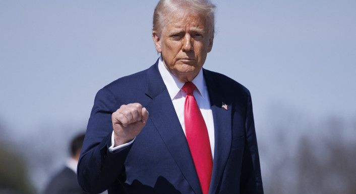 Trump vor hellblauem Hintergrund, mit halb erhobener Faust