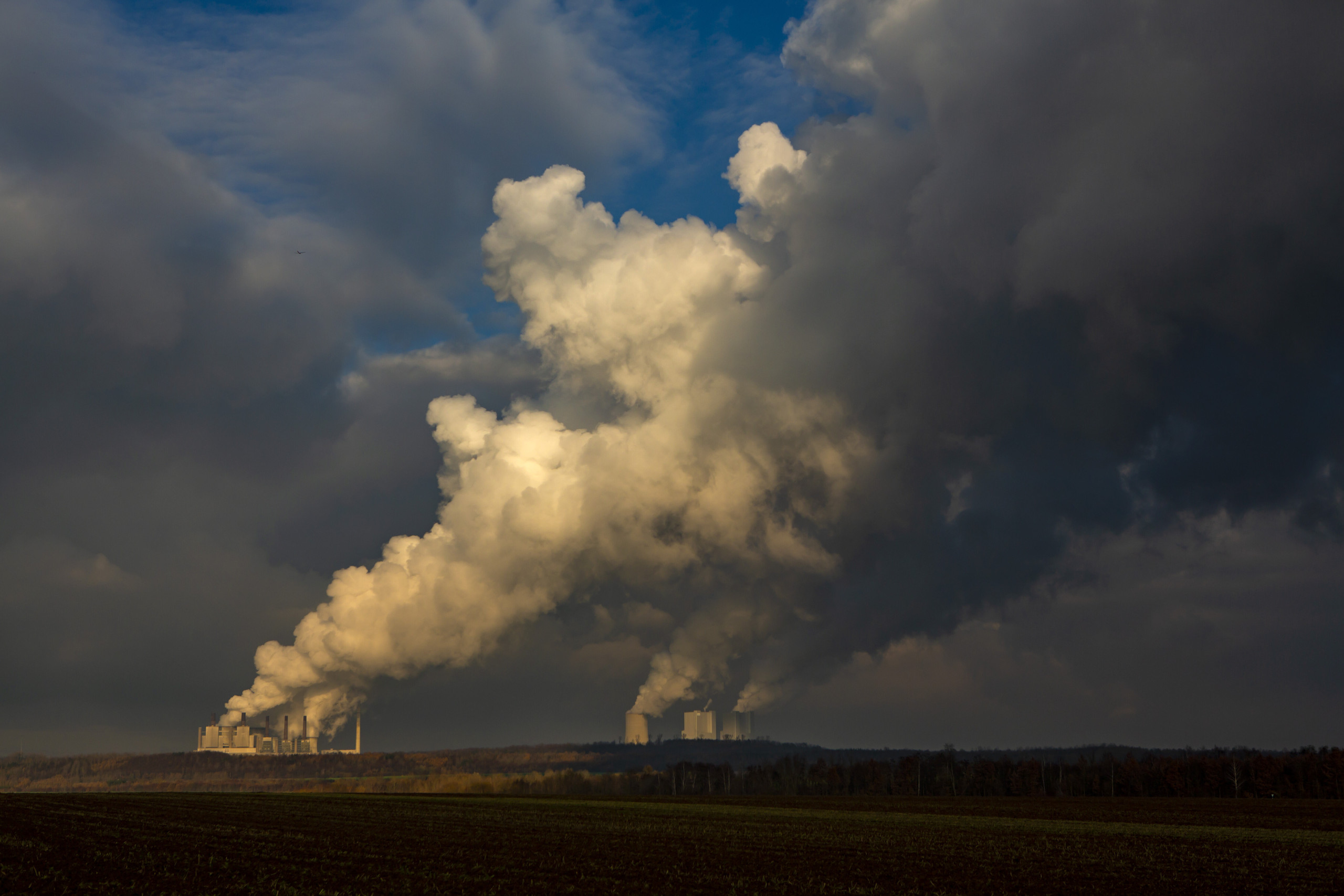 In der Ferne verschmilzen vier grosse Rauchwolken aus einem Kohlekraftwerk der RWA zu einer riesigen Rauchwolke, die beinahe das ganze Bild ausfüllt.