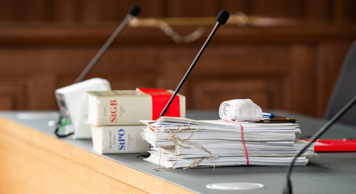 Unterlagen sowie die Strafprozessordnung (StPO) und Strafgesetzbuch (StGB) liegen auf einem Tisch im Gericht
