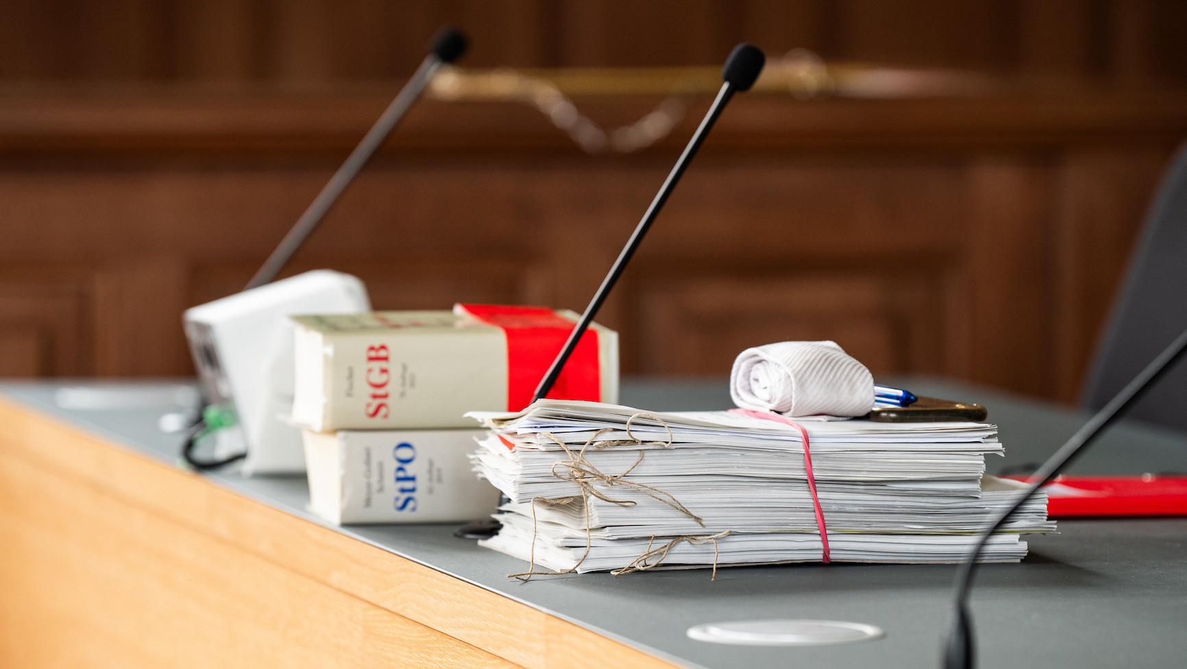Unterlagen sowie die Strafprozessordnung (StPO) und Strafgesetzbuch (StGB) liegen auf einem Tisch im Gericht