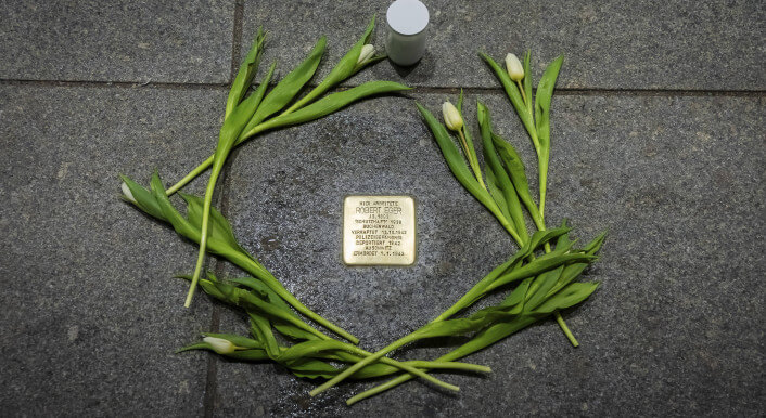 Zweige sind um einen Stolperstein gereiht