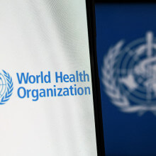 Auf einem Bildschirm ist das Logo der Weltgesundheitsorganisation zu sehen