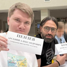 Aeza-Chefs Arseniy Penzev (links) und Juri Boz (rechts) aus Russland halten Schilder in einem Seminarraum hoch