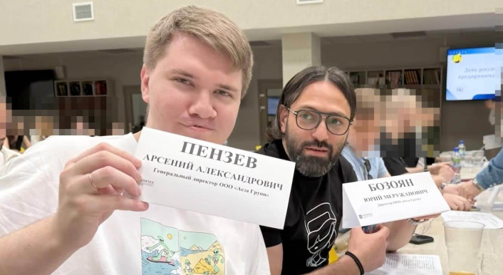 Aeza-Chefs Arseniy Penzev (links) und Juri Boz (rechts) aus Russland halten Schilder in einem Seminarraum hoch