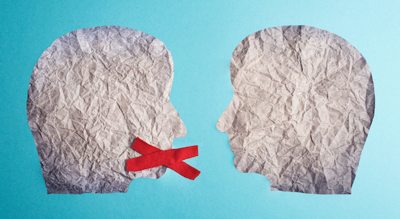 Zwei ausgeschnittene Gesichter aus Papier stehen sich gegenüber, eines hat ein rotes X vor dem Mund.