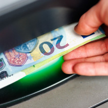 Eine Hand nimmt Scheine an einem Geldautomaten entgegen