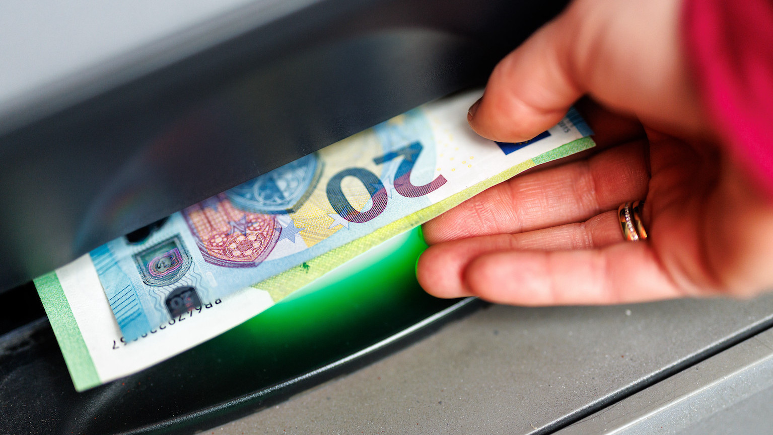 Eine Hand nimmt Scheine an einem Geldautomaten entgegen