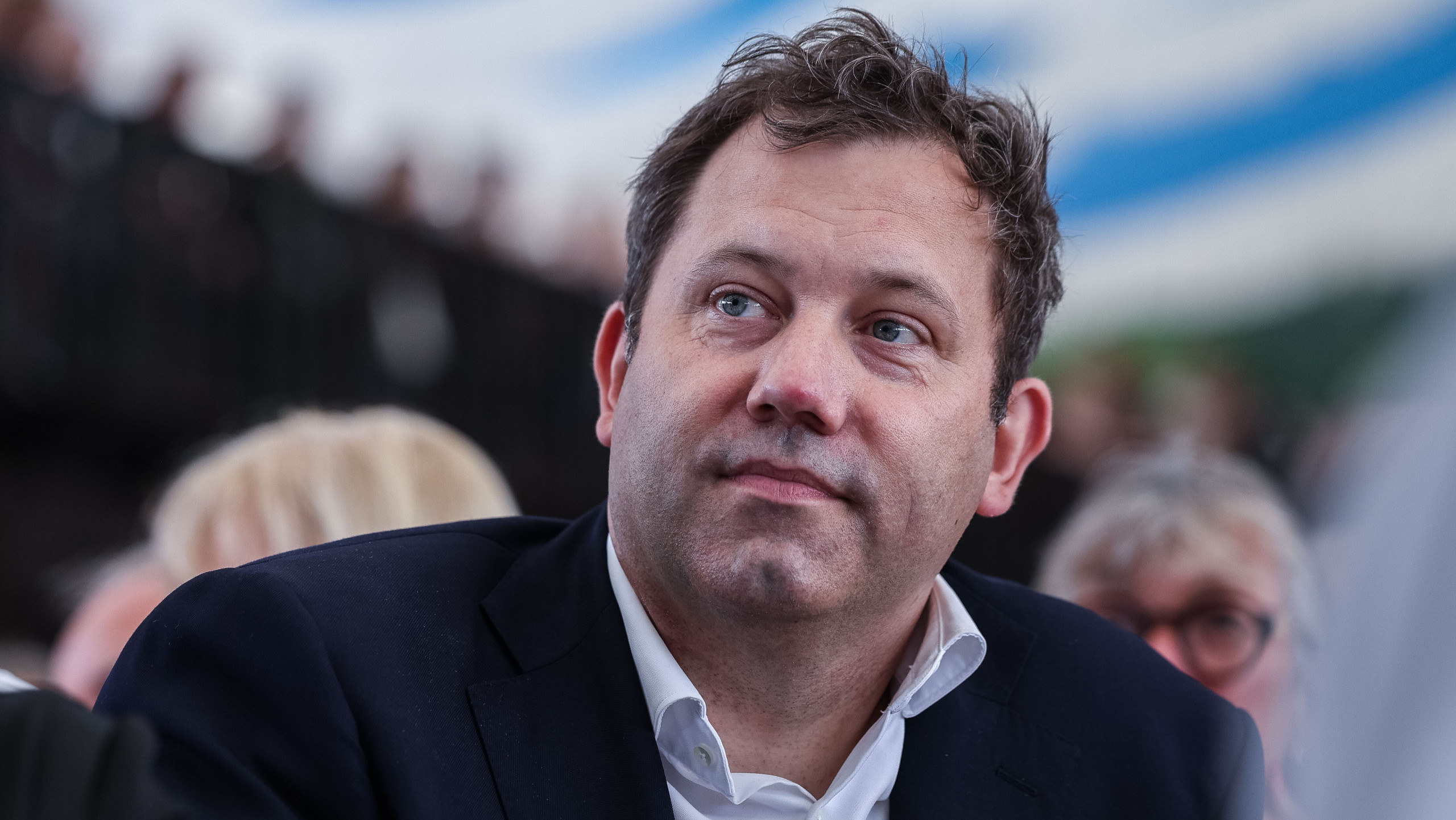 Lars Klingbeil sitzt bei der Cranger Kirmes zwischen Menschen. Er trägt ein dunkles Sakko und ein weißes Hemd.