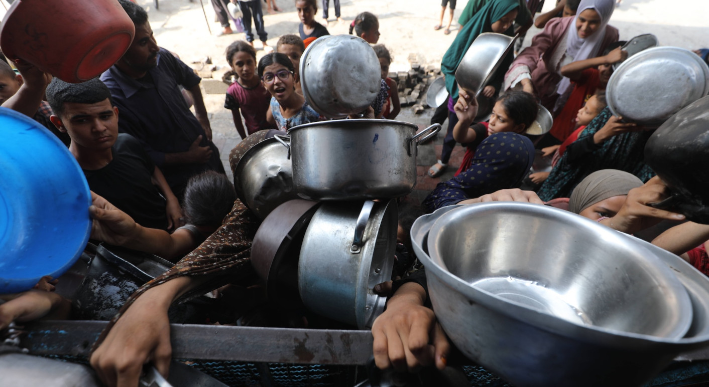 Palestinians wait to receive food from a charity kitchen, amid a hunger crisis, in Bureij