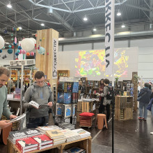Stand des CORRECTIV.Verlags auf einer Buchmesse, Menschen blättern in Büchern