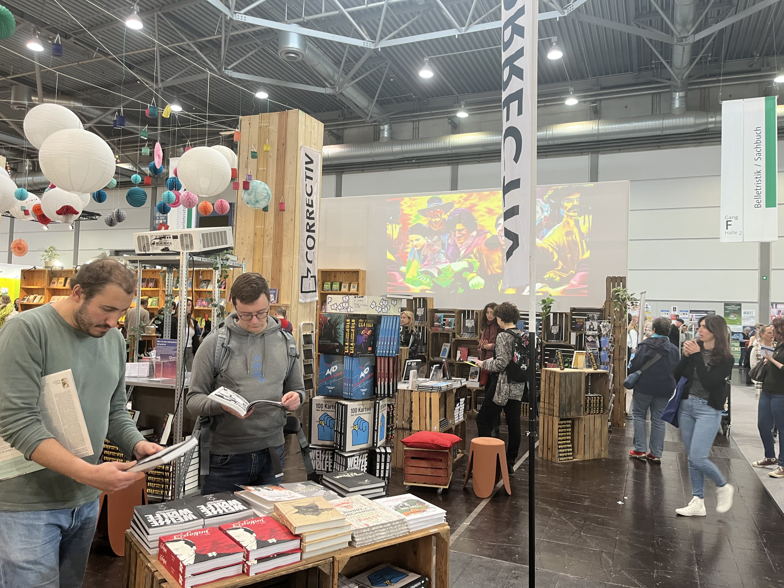 Stand des CORRECTIV.Verlags auf einer Buchmesse, Menschen blättern in Büchern