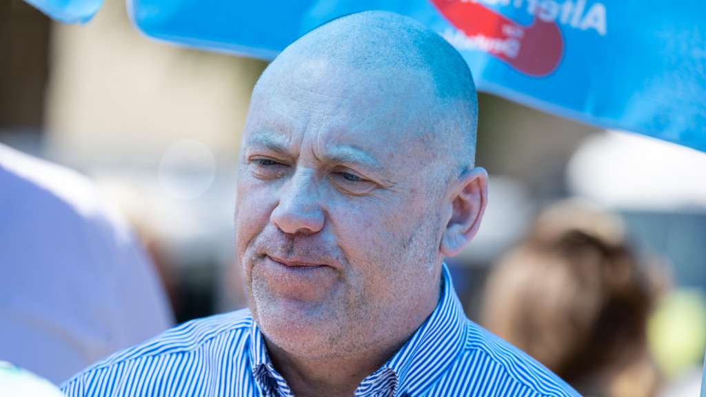 Joachim Frank steht bei einer Kundgebung unter einem Pavillon in AfD-Farben