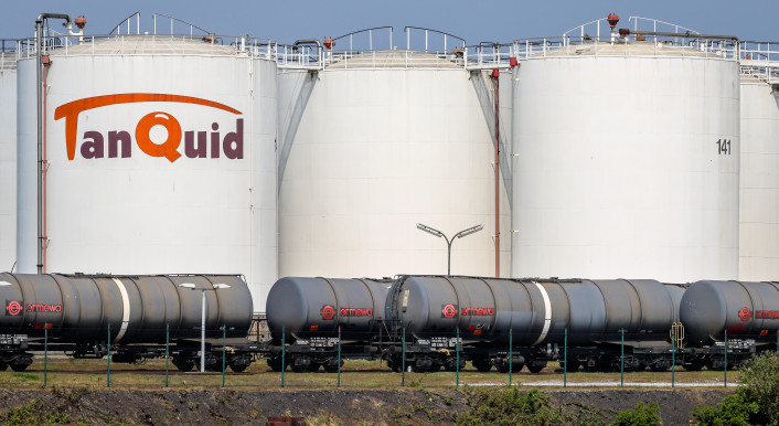 Diese Bild zeigt drei große weiße Silos der Firma Tanquid. Dort lagern Mineralöl, Gase oder andere Stoffe. Davor sind graue Güterzüge zu sehen. Foto:Rupert Oberhäuser/picture alliance