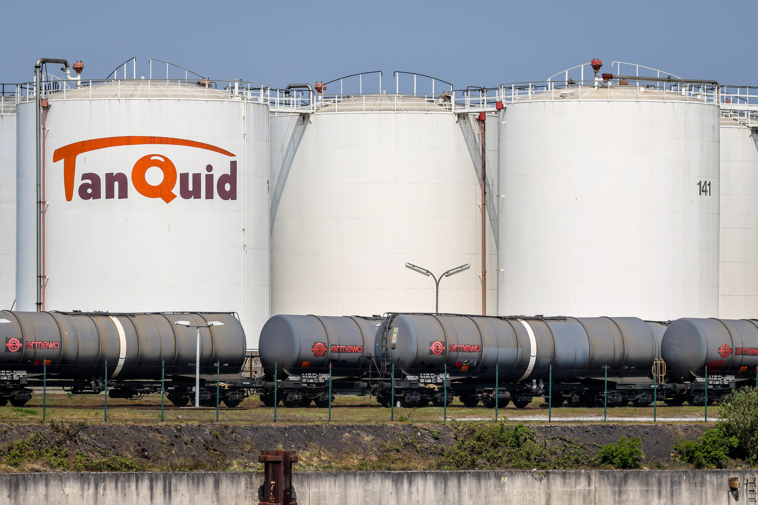 Diese Bild zeigt drei große weiße Silos der Firma Tanquid. Dort lagern Mineralöl, Gase oder andere Stoffe. Davor sind graue Güterzüge zu sehen. Foto:Rupert Oberhäuser/picture alliance
