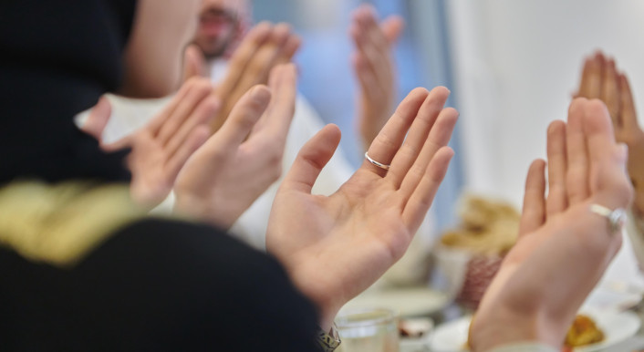 Betende Hände an einem Tisch mit Essen