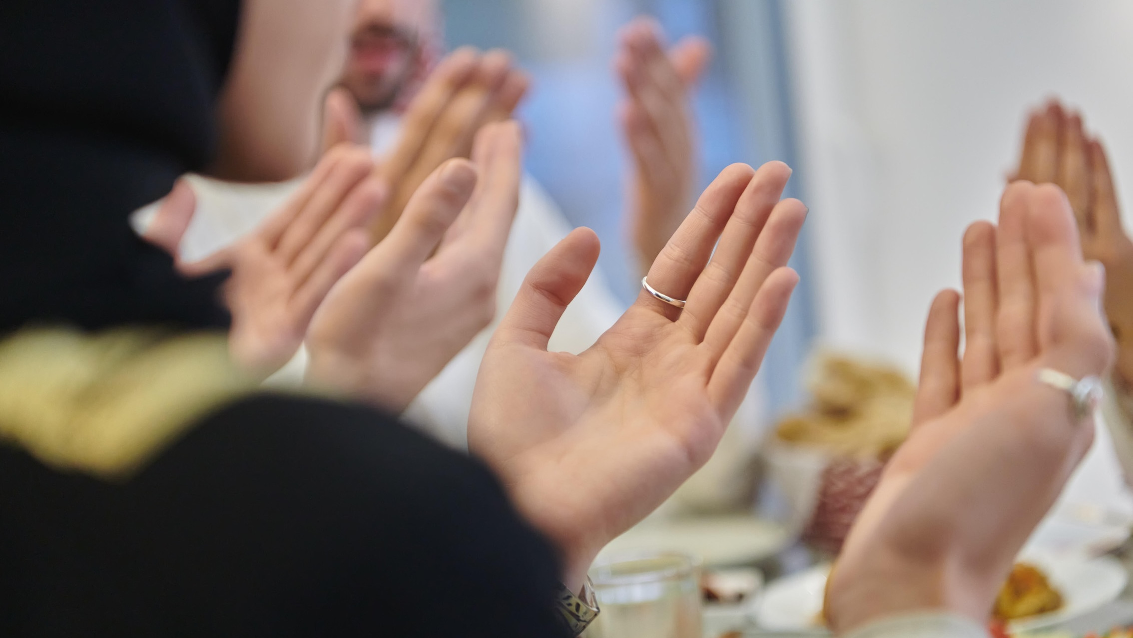 Betende Hände an einem Tisch mit Essen