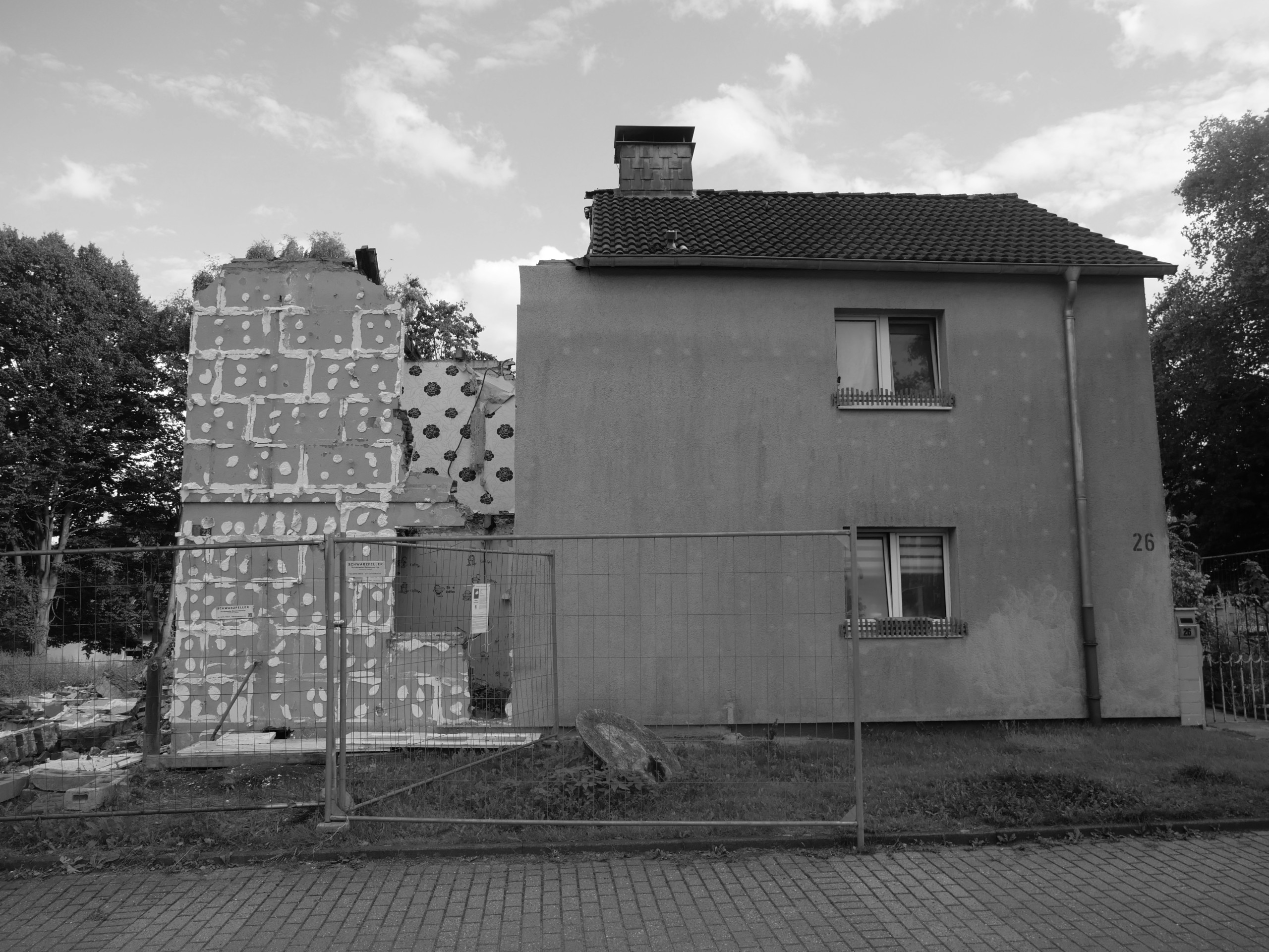 Ein zur Hälfte abgerissenes Wohnhaus, darum ein Bauzaun.