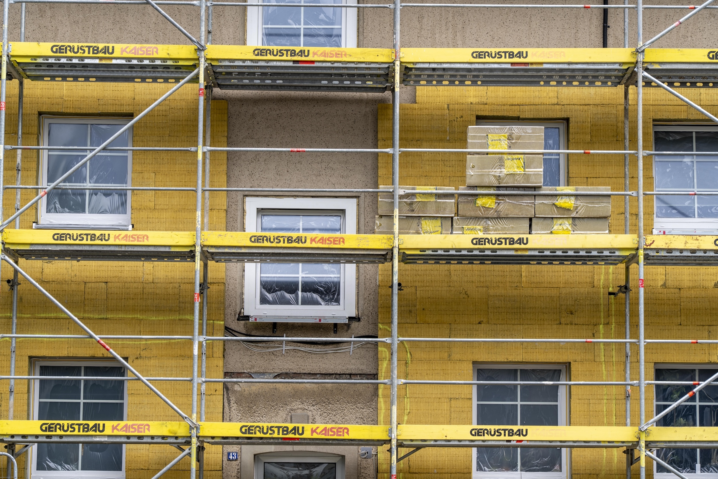Ein Gerüst vor einer Hausfassade, die gedämmt wird.