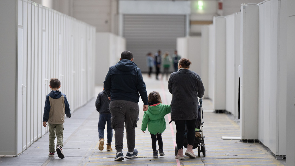 Eine Flüchtlingsfamilie geht durch die zu einer Massenunterkunft umfunktionierten Messehalle in Frankfurt.