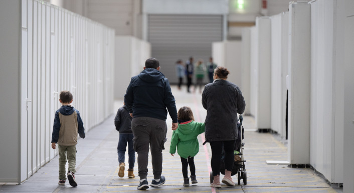 Eine Flüchtlingsfamilie geht durch die zu einer Massenunterkunft umfunktionierten Messehalle in Frankfurt.