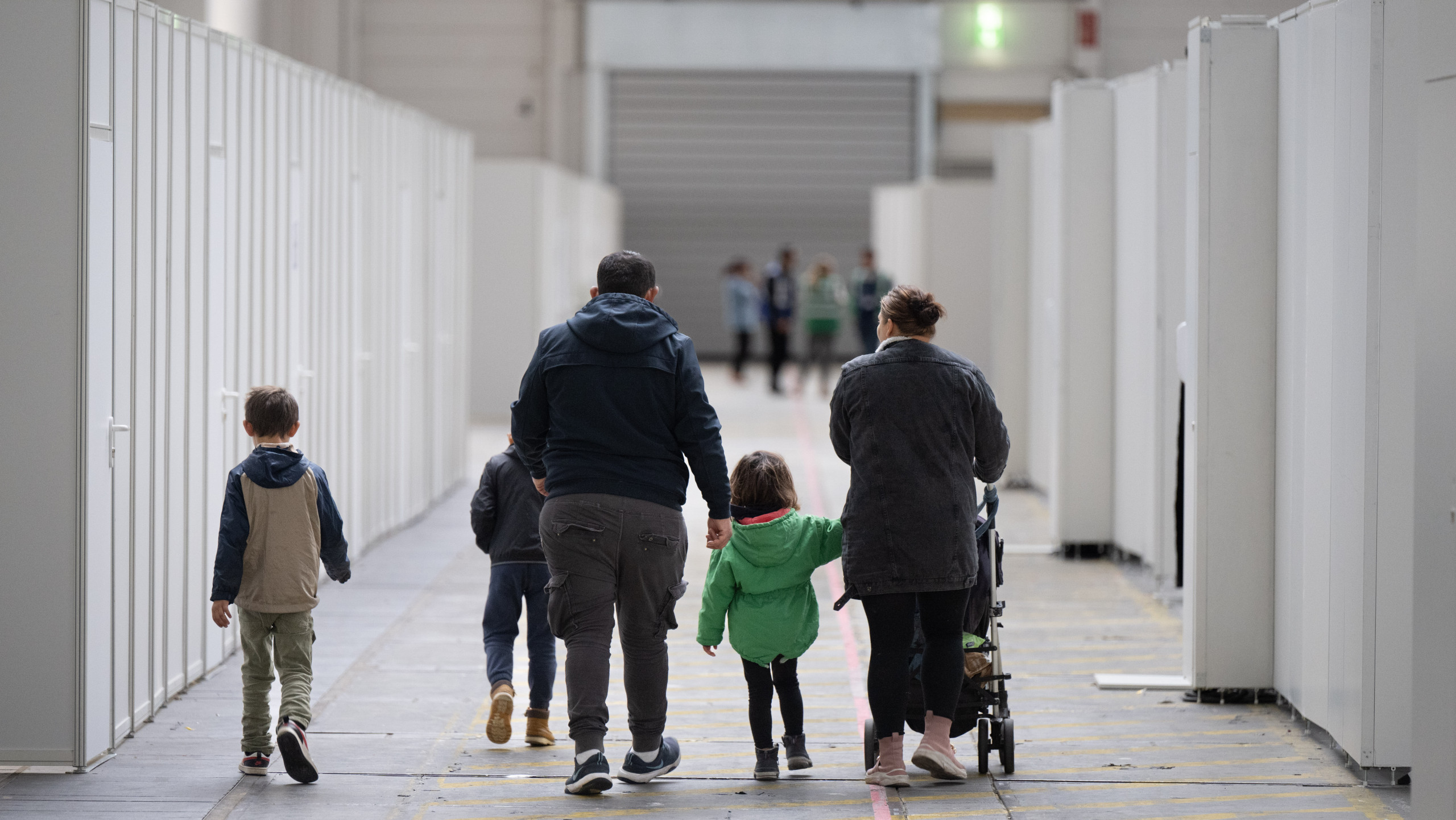 Eine Flüchtlingsfamilie geht durch die zu einer Massenunterkunft umfunktionierten Messehalle in Frankfurt.
