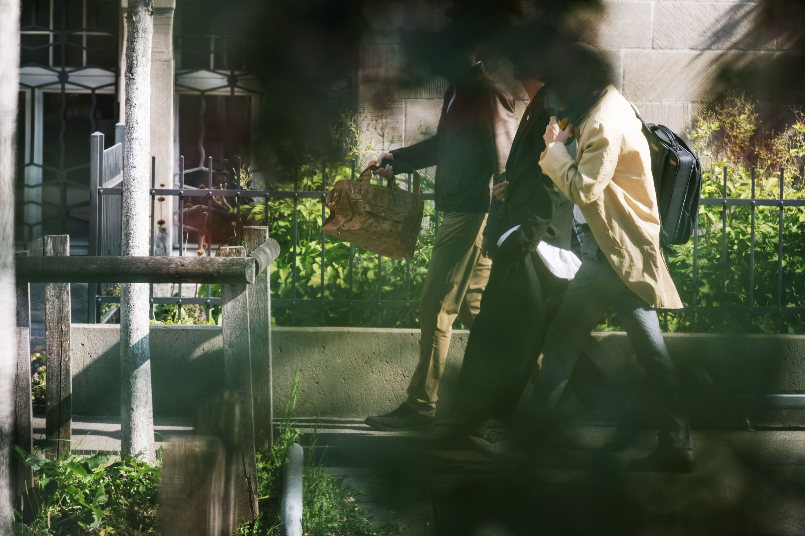 Drei gut angezogene Männer laufen auf der Strasse. Einer trägt eine grosse Luxus-Tasche aus Leder. Sie treffen sich mit Banken, Kanzleien und Steuerämtern. Sie wollen zeigen, wie wenig Steuern Super-Reiche zahlen.