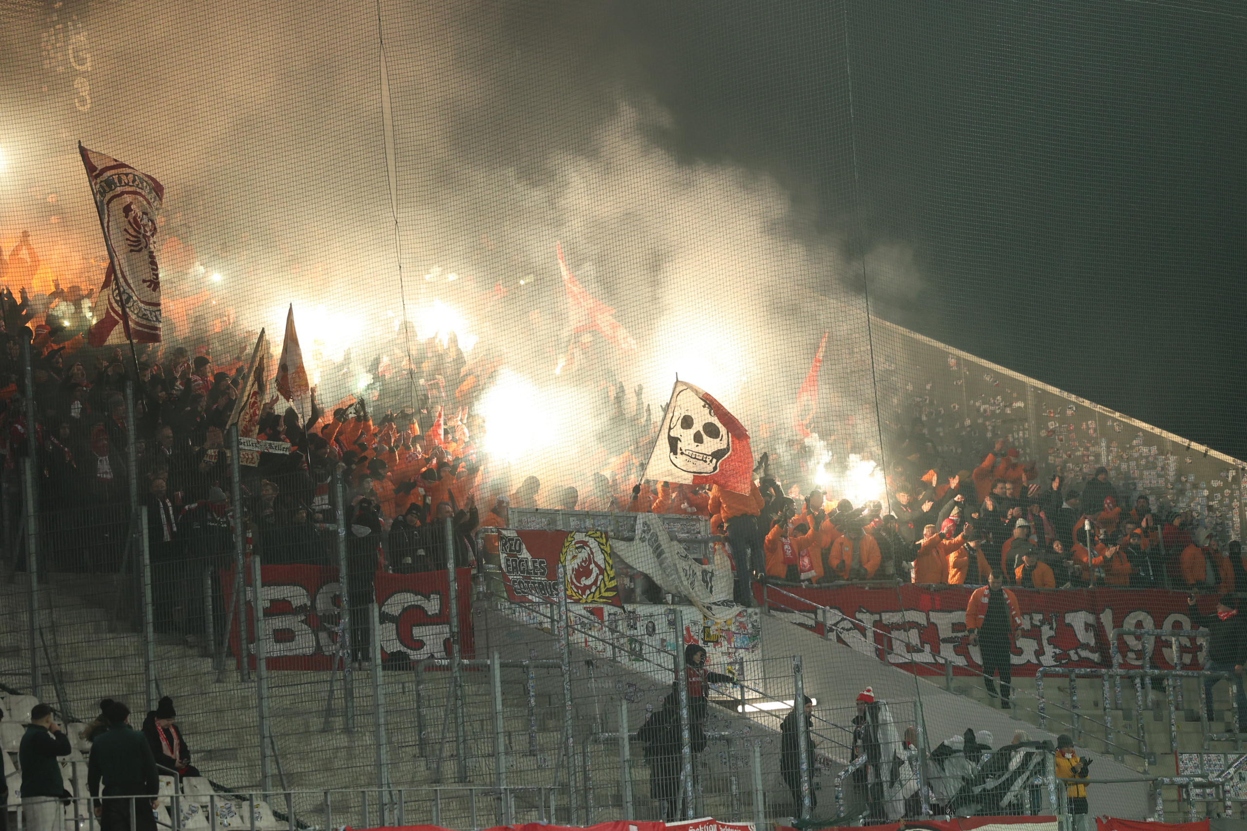 Fans des FC Energie Cottbus zünden Bengalos und schwenken eine Totenkopf-Fahne bei einem Auswärtsspiel.