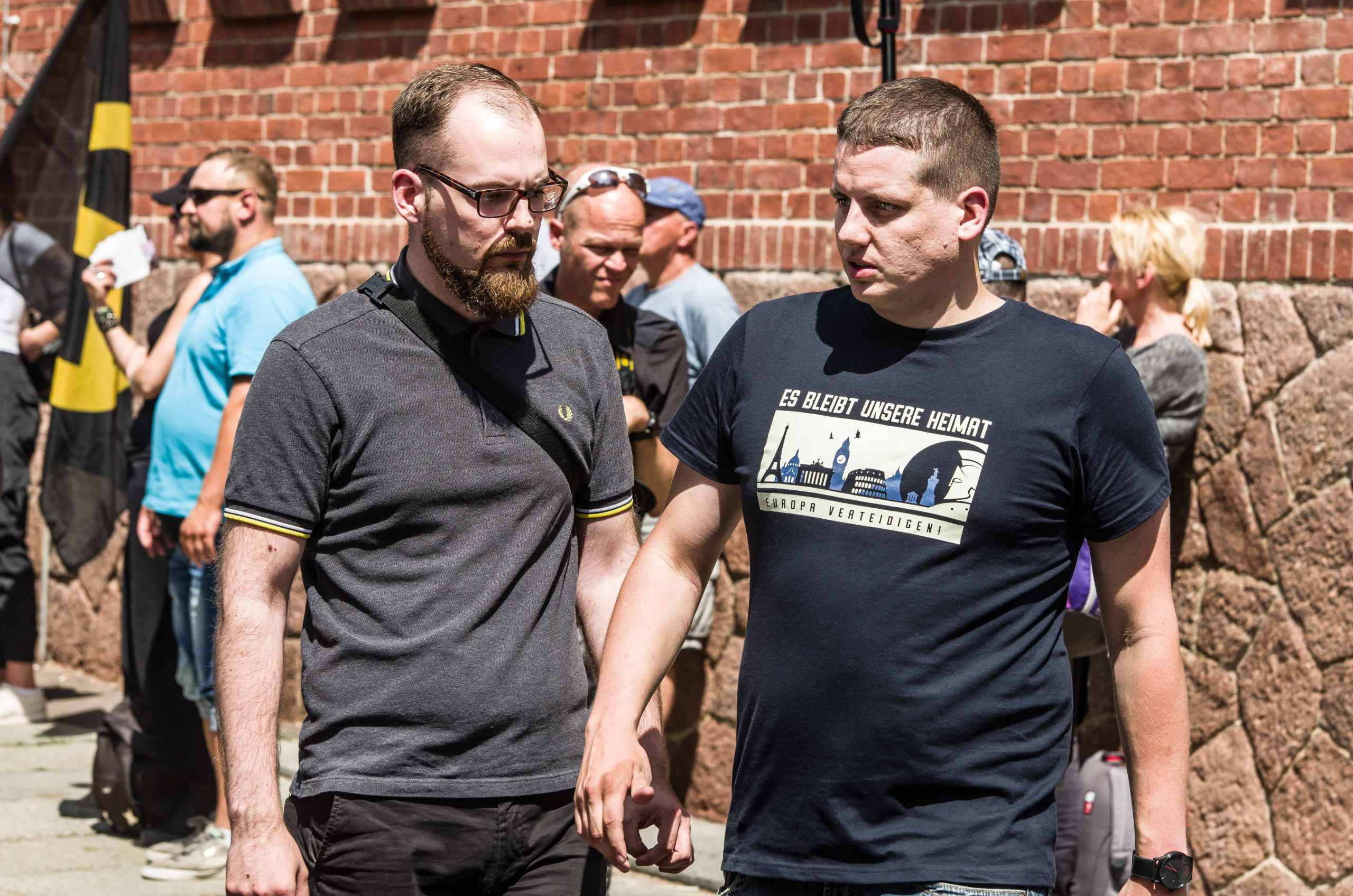 Robert Timm, Ex-Regionalchef der Identitären Berlin-Brandenburg, ist auf einer Demonstration der Identitären Bewegung zu sehen. Er blickt grimmig. Sein Gegenüber trägt ein T-shirt mit der Aufschrift "Europa verteidigen"