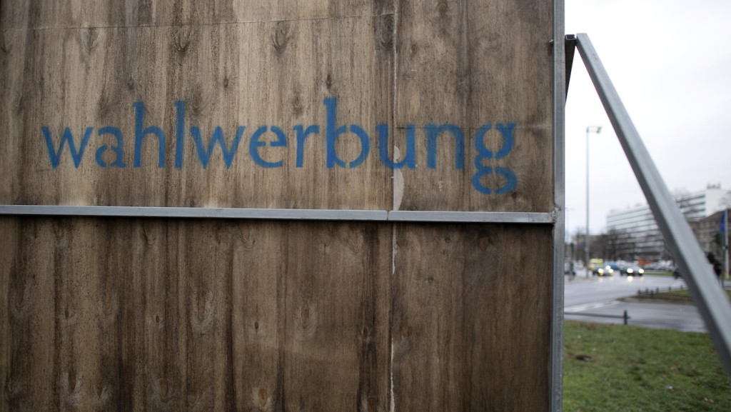 „Wahlwerbung“ steht hinten auf einer Werbetafel an einer Straße