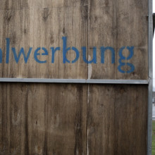 „Wahlwerbung“ steht hinten auf einer Werbetafel an einer Straße