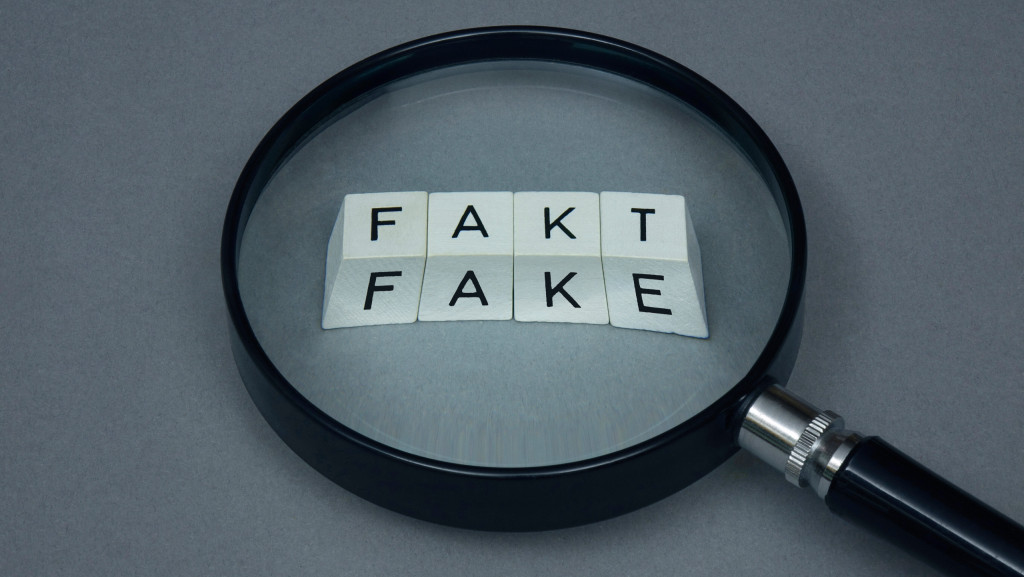 Eine Lupe zeigt auf die Wörter "Fakt" und "Fake".