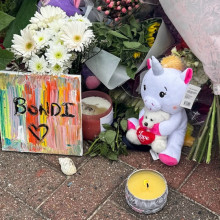Auf dem Pflastersteinen liegen Blumen und Stofftiere, auf einer Leinwand steht "Bondi".