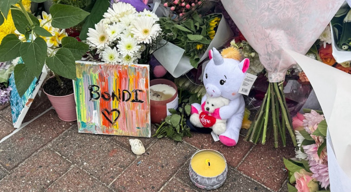 Auf dem Pflastersteinen liegen Blumen und Stofftiere, auf einer Leinwand steht "Bondi".