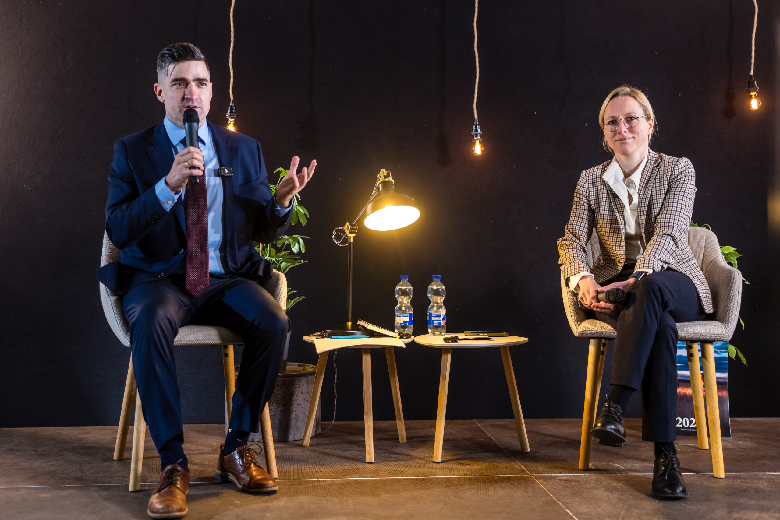 Der Rechtsextremist Martin Sellner und die AfD-Landtagsabgeordnete Lena Kotré sitzen auf einer Bühne und reden.
