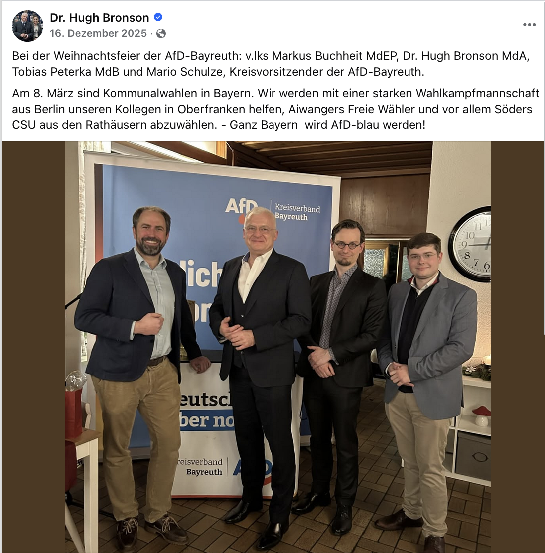 Hugh Bronson und Tobias Peterka neben zwei weiteren AfD-Männern vor einem AfD-Plakat, posierend