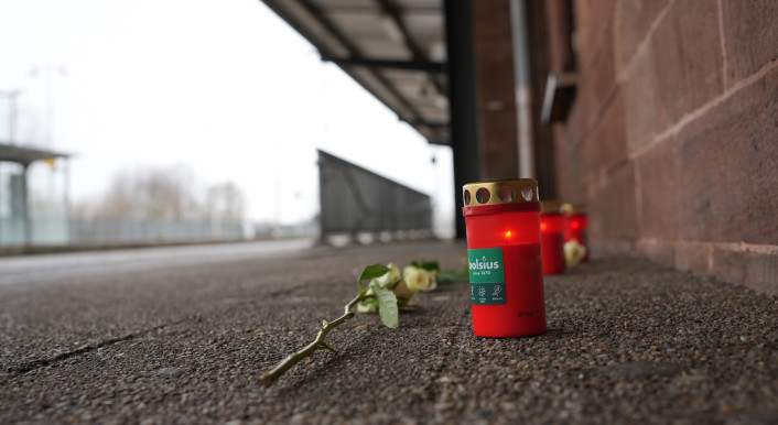 Eine Blume und Kerzen liegen am Bahnsteig