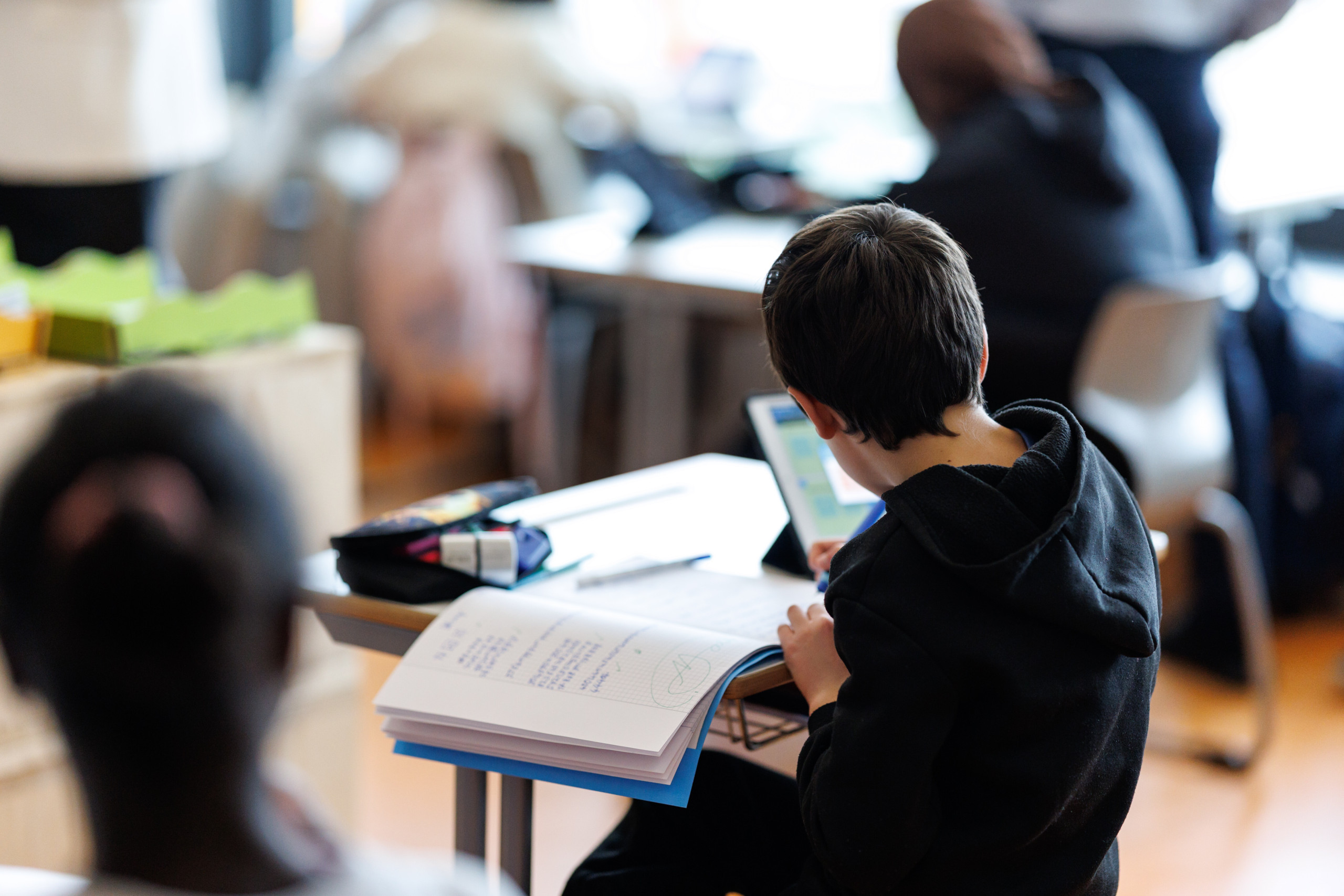 Mehrere Kinder sitzen im Klassenraum und lernen.