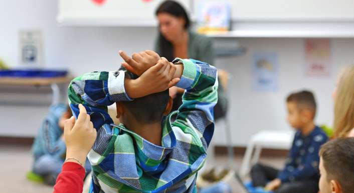 Ein Kind mit Migrationshintergrund meldet sich im Unterricht