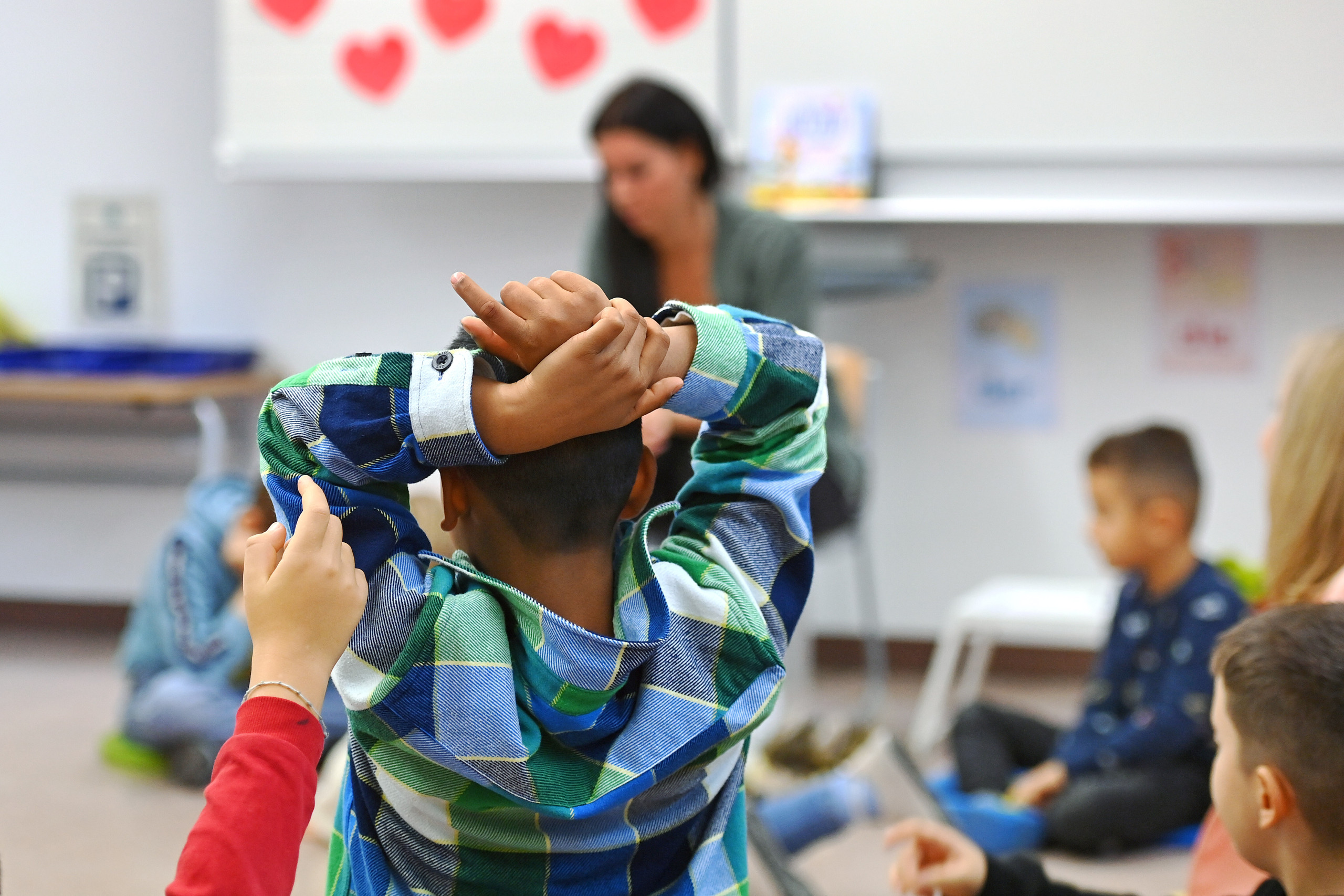 Ein Kind mit Migrationshintergrund meldet sich im Unterricht