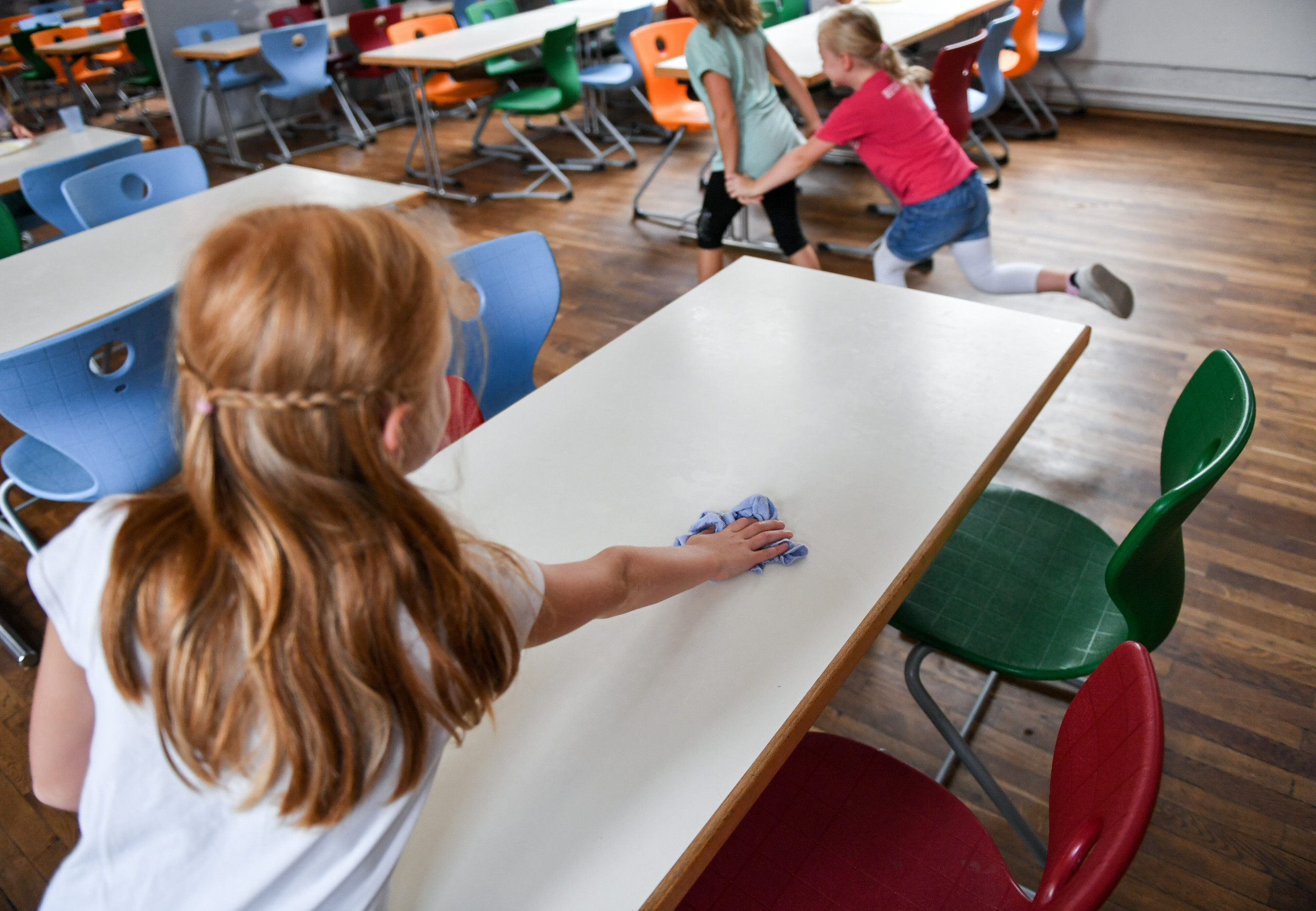 Eine Schülerin wischt nach dem Mittagessen in der Mensa in der Grundschule den Tisch ab.