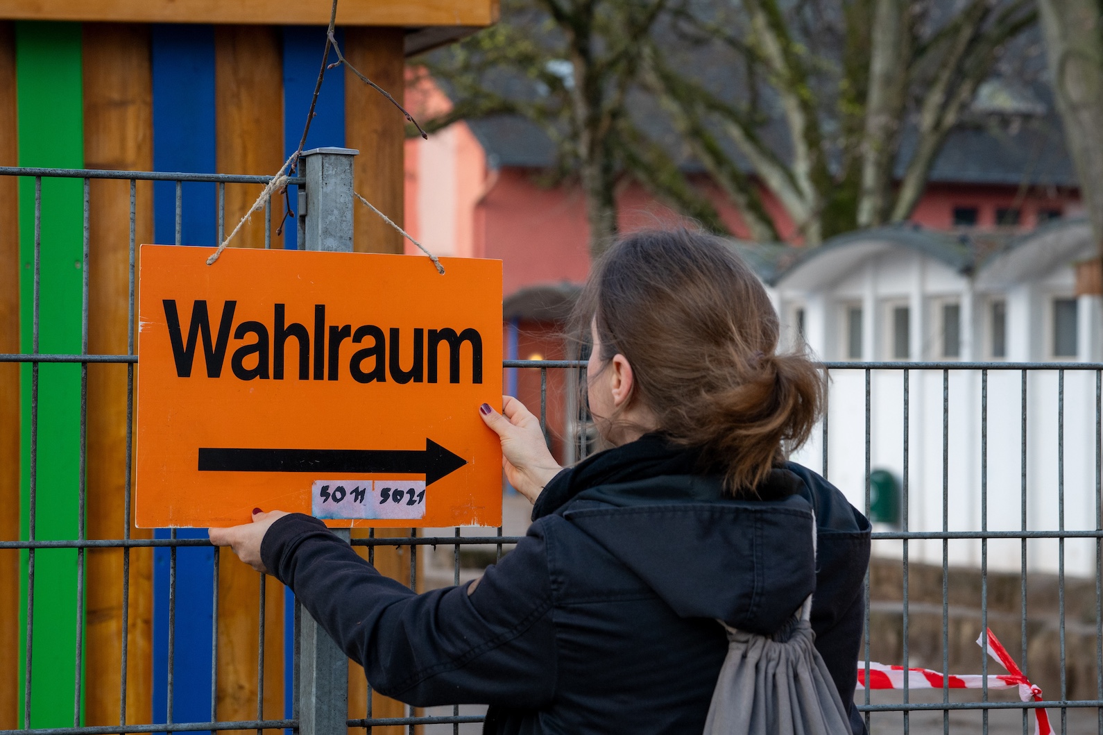 Frau hängt Schild zum Wahlraum bei der Landtagswahl in Rheinland-Pfalz im März 2026 auf