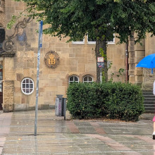 Frau läuft mit Regenschirm über die Straße in Bielefeld, im Hintergrund sind Wahl-Plakate aufgestellt