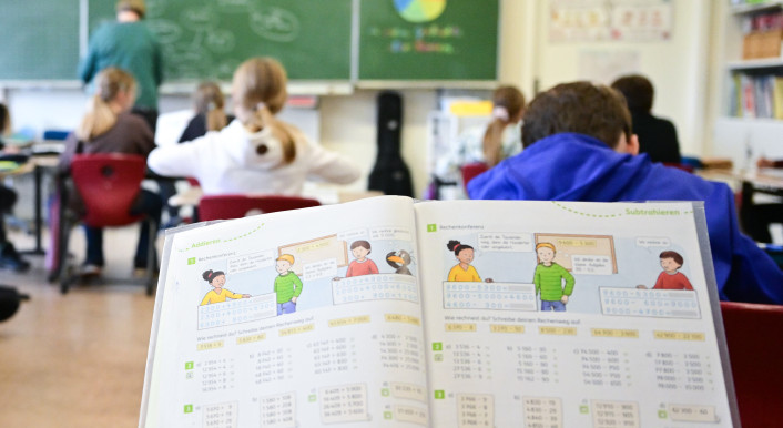 Kinder sitzen in einem Klassenraum und blicken zur Tafel.